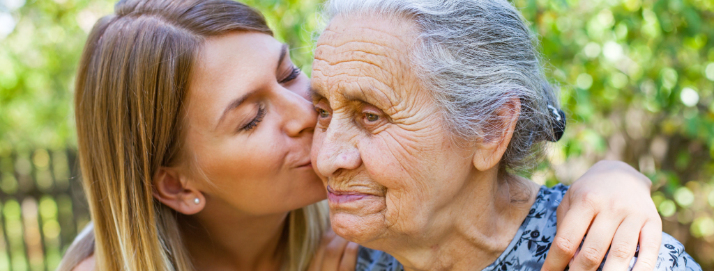 Elderly woman being kissed by her daughter